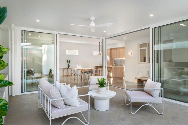 Covered alfresco area connected to an open-plan kitchen and dining space through large sliding glass doors.
