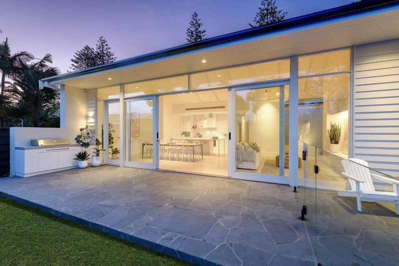 Light-filled rear bungalow extension in Adelaide with large glass doors, open-plan living and a paved alfresco area.